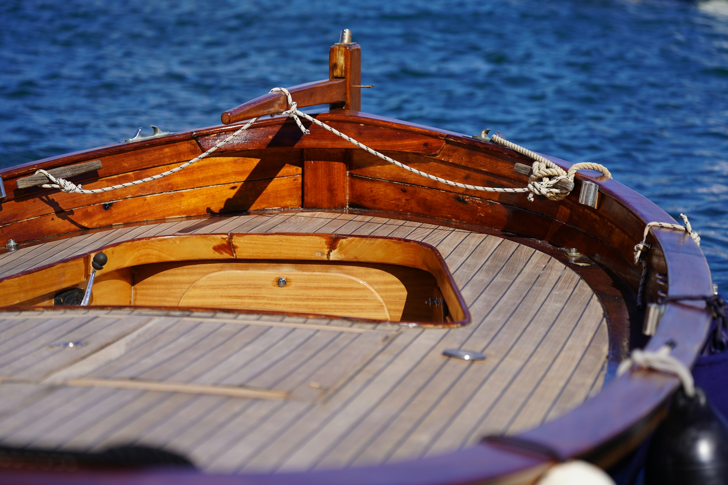 Hand-varnished mahogany bow rails of a classic cruiser at the dock