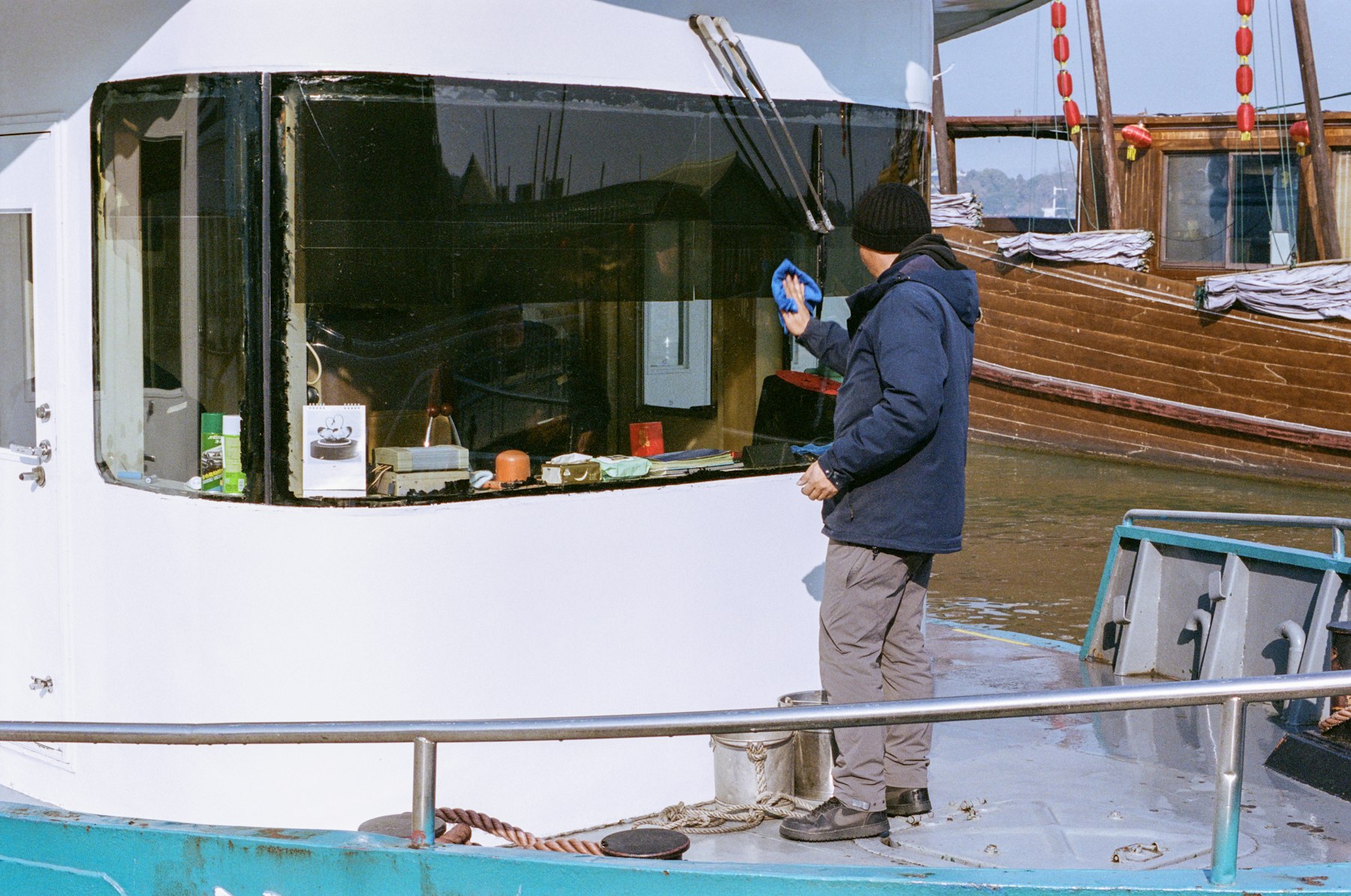 Detailer hand-cleaning the cabin windows of a moored cruiser at a Memphis marina